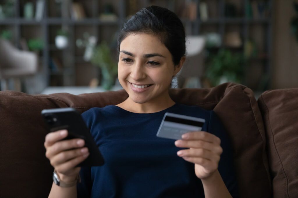 mulher abrindo conta no exterior pelo celular enquanto segura o cartão