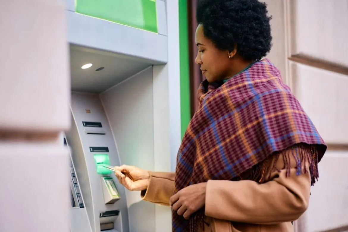Uma mulher negra sacando dinheiro no caixa sacando dinheiro para ilustrar um texto sobre o banco do brasil em portugal