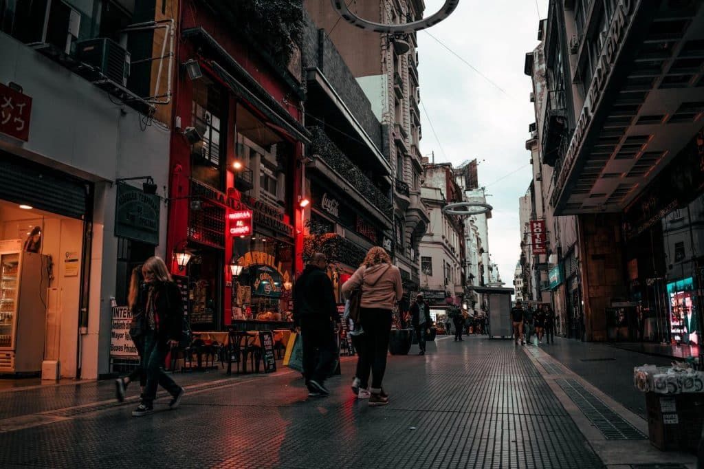 Destinos na América do Sul: Pessoas transitando por uma rua de comércios em Buenos Aires, na Argentina.