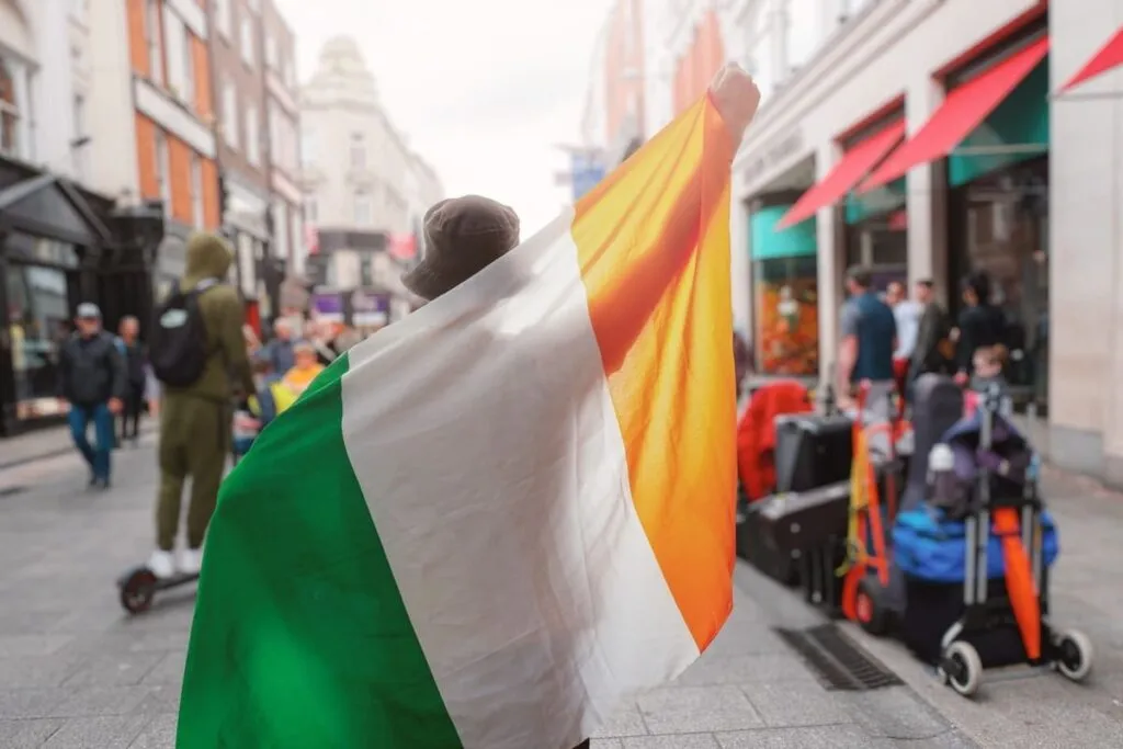 Imagem de um homem branco com a bandeira na Irlanda simbolizando se é difícil morar no país.
