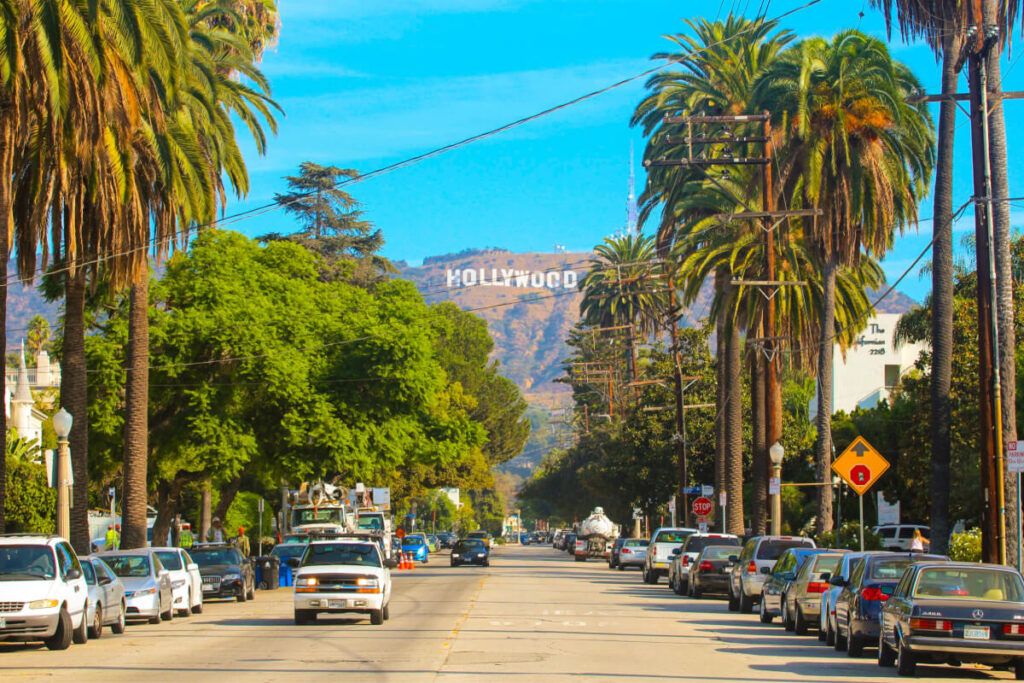 Rua calma de Los Angeles, com palmeiras e letreiro de Hollywood ao fundo