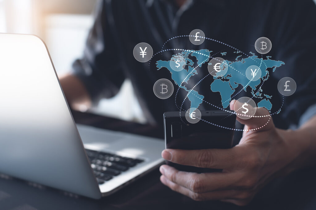 homem mexendo no computador e no celular para analisar qual é o melhor meio para fazer transferência
