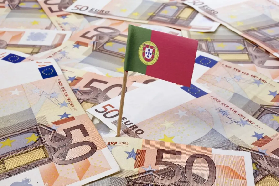 Bandeira de Portugal fincada em notas de euros, onde o banco Activobank está localizado e estrangeiros podem abrir conta