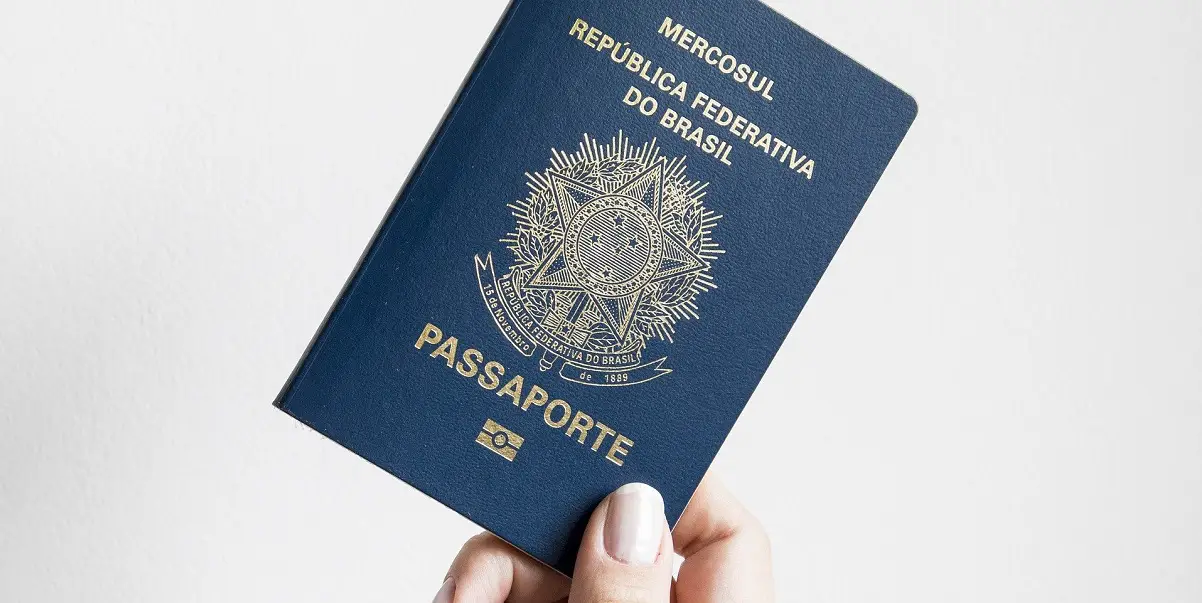 Foto de uma mão segurando um passaporte com fundo branco