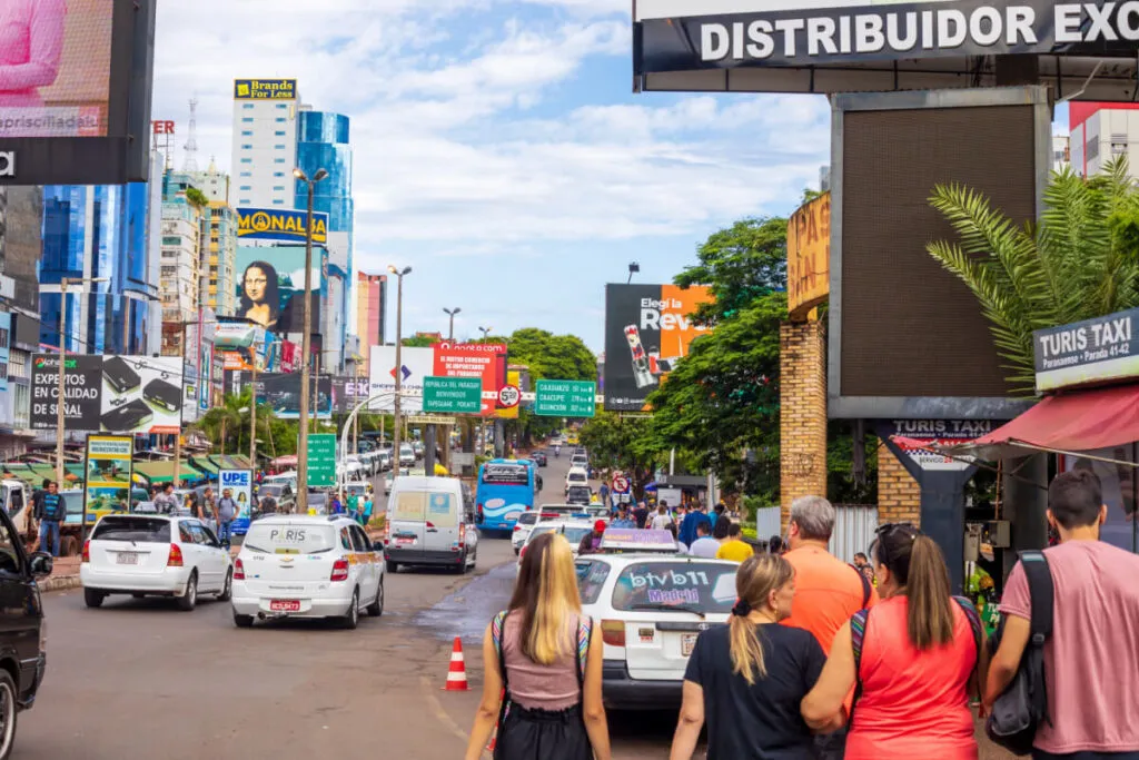 Rua do Paraguai com pedestres, carros e comércio.