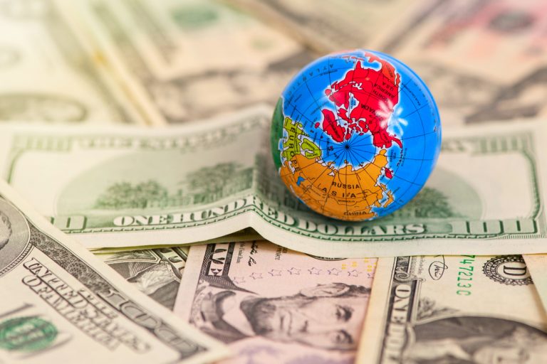 Fluxo cambial: mapa do mundo em globo sobre notas de dólar americano