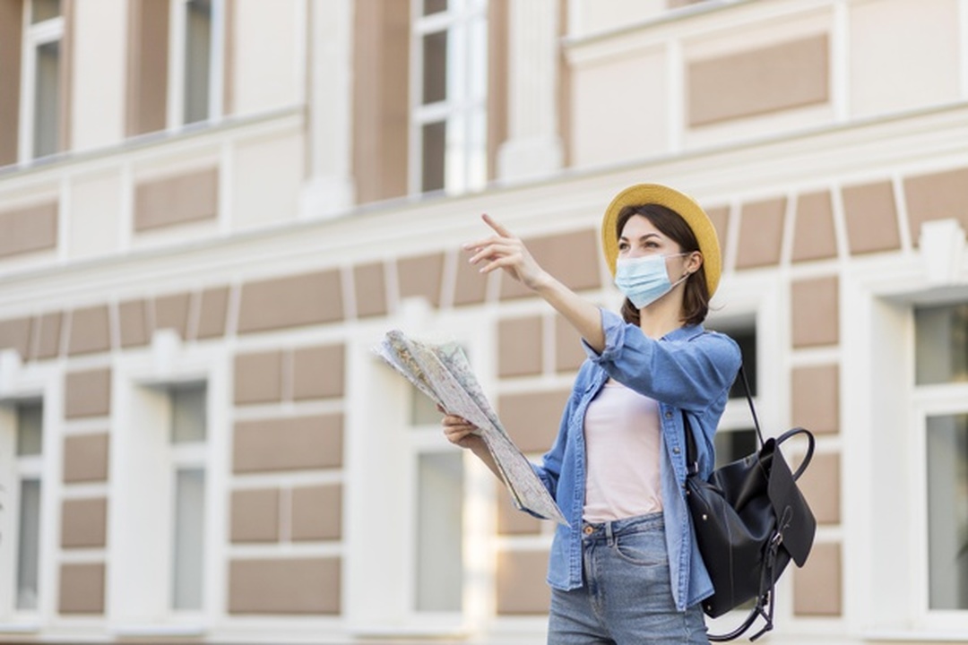 Turismo: jovem mulher viajante com chapéu e máscara facial