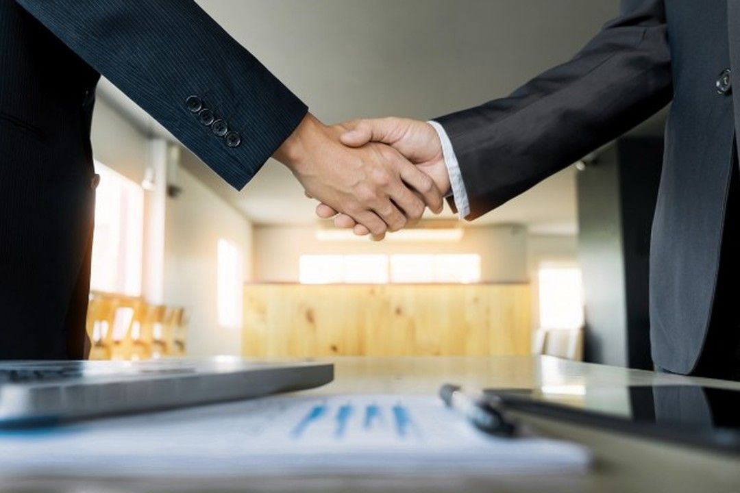 Fusão, incorporação, cisão e joint venture: dois homens de negócios apertando as mãos