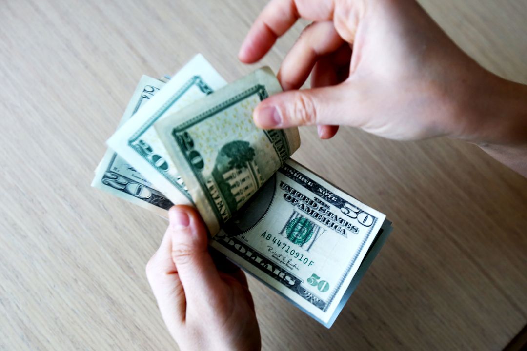 Foto de duas mãos segurando notas de dólares