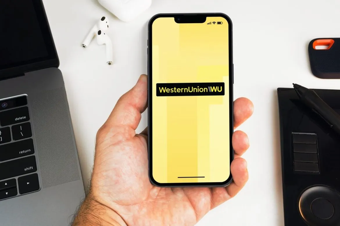 Close-up mãos segurando smartphone com o logo da Western Union