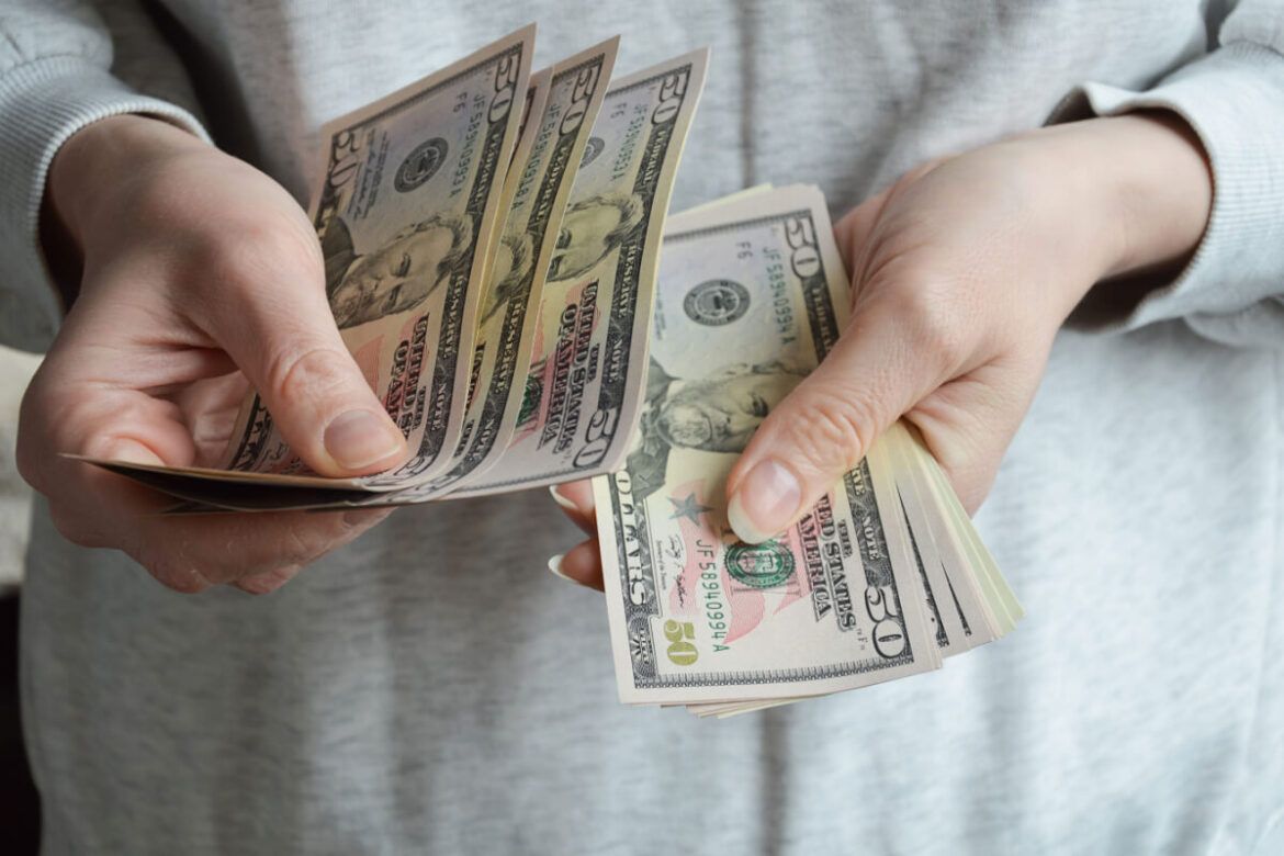 Imagem de uma mulher segurando notas de dólar