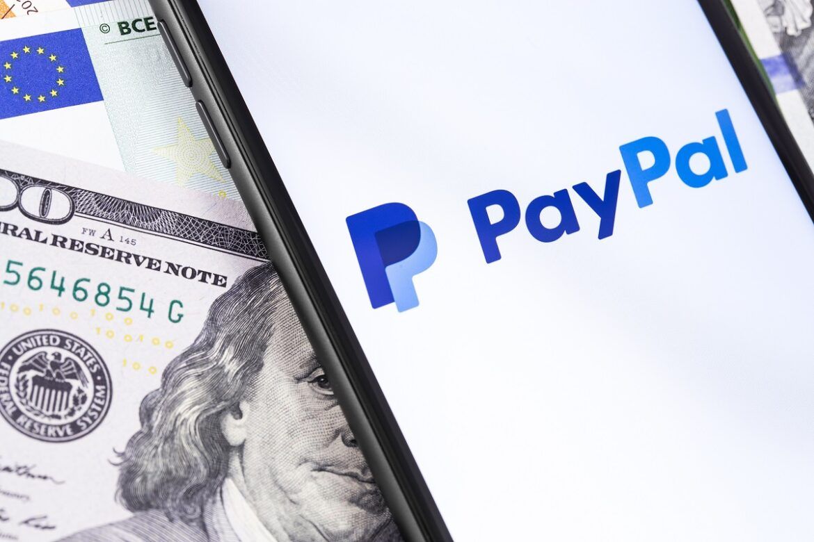 Imagem com celular em cima de notas de dólares simulando mostrar como ganhar dinheiro pelo PayPal