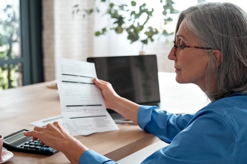 Uma mulher analisando alguns documentos e pesquisando alguma informação