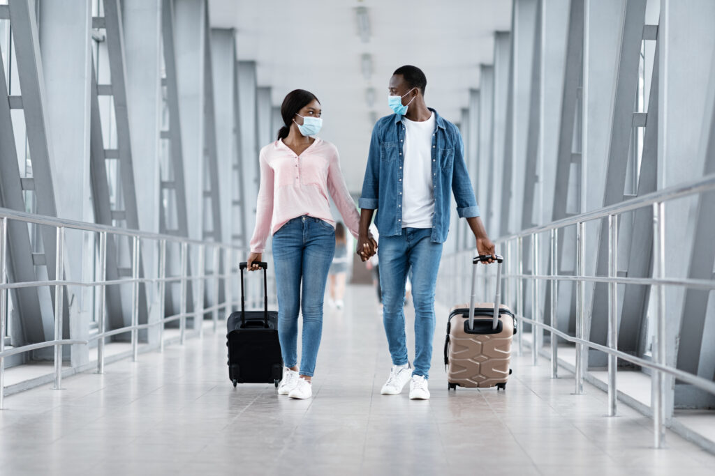 Casal em viagem Jovem casal de mãos dadas e máscara contra a covid, no aeroporto