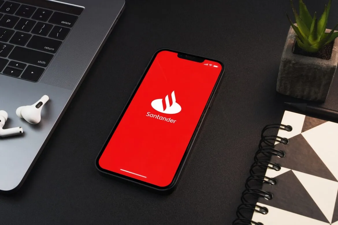 Foto de um celular em cima de uma mesa com o logotipo do Santander na tela