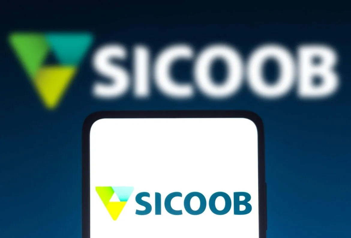 Imagem com tela de celular com o logo do Banco Sicoob e, em segundo plano, o logo do Sicoob desfocado