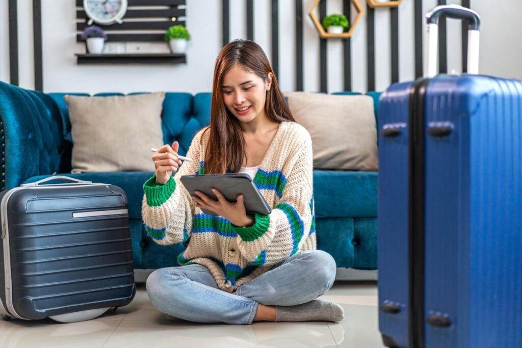 Mulher sentada no chão e acessando tablet para vender milhas aéreas. 