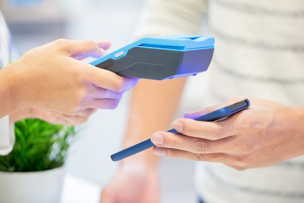 Maquininha de cartão azul lendo pagamento no smartphone