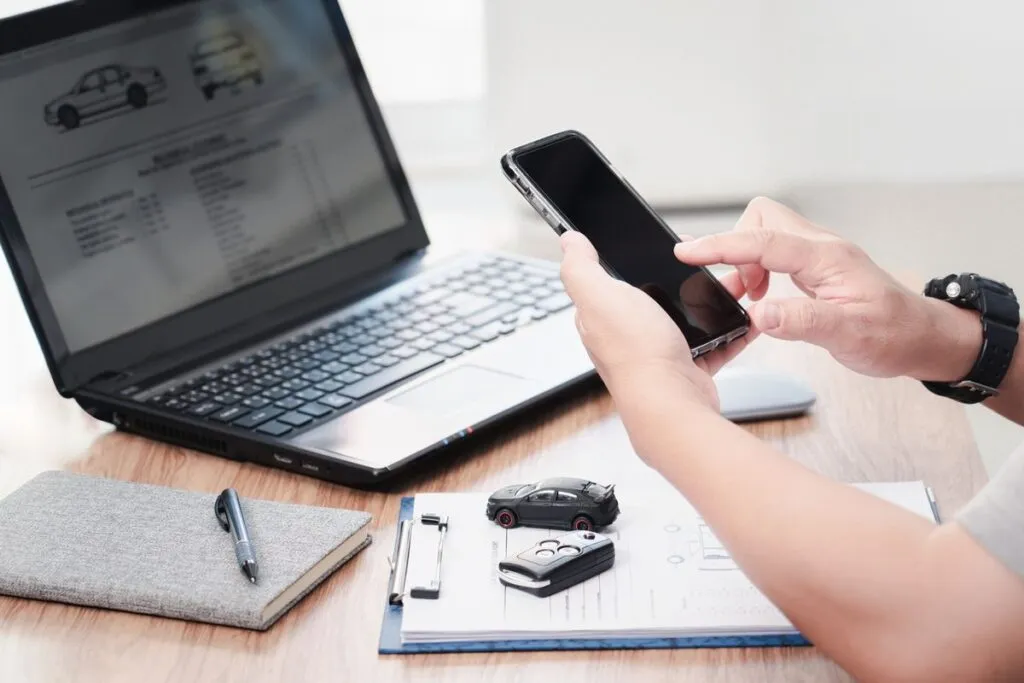 Mão de homem acessando o smartphone e notebook no escritório.