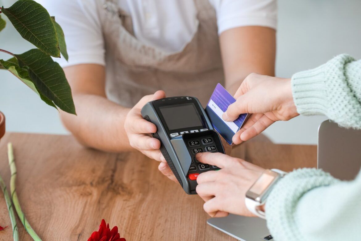 Mãos de homem segurando o cartão de crédito e uma maquininha