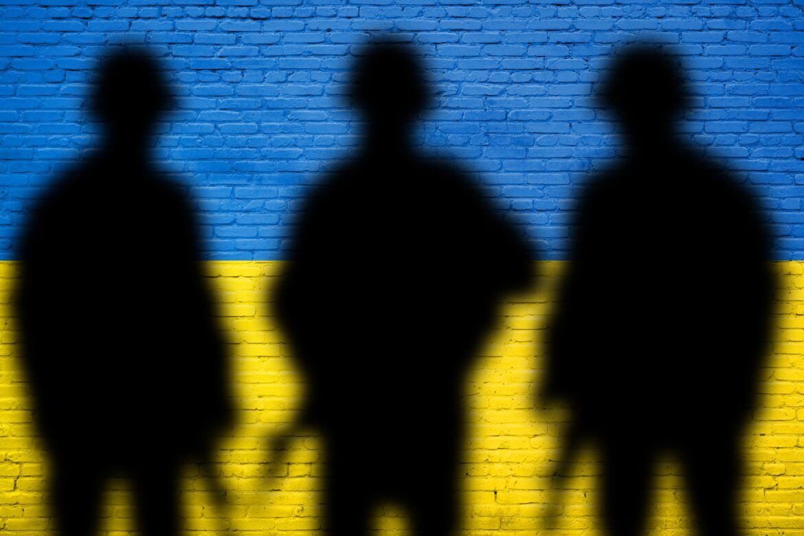 Bandeira Ucrânia em forma de parede, com sombra de 3 pessoas com armas