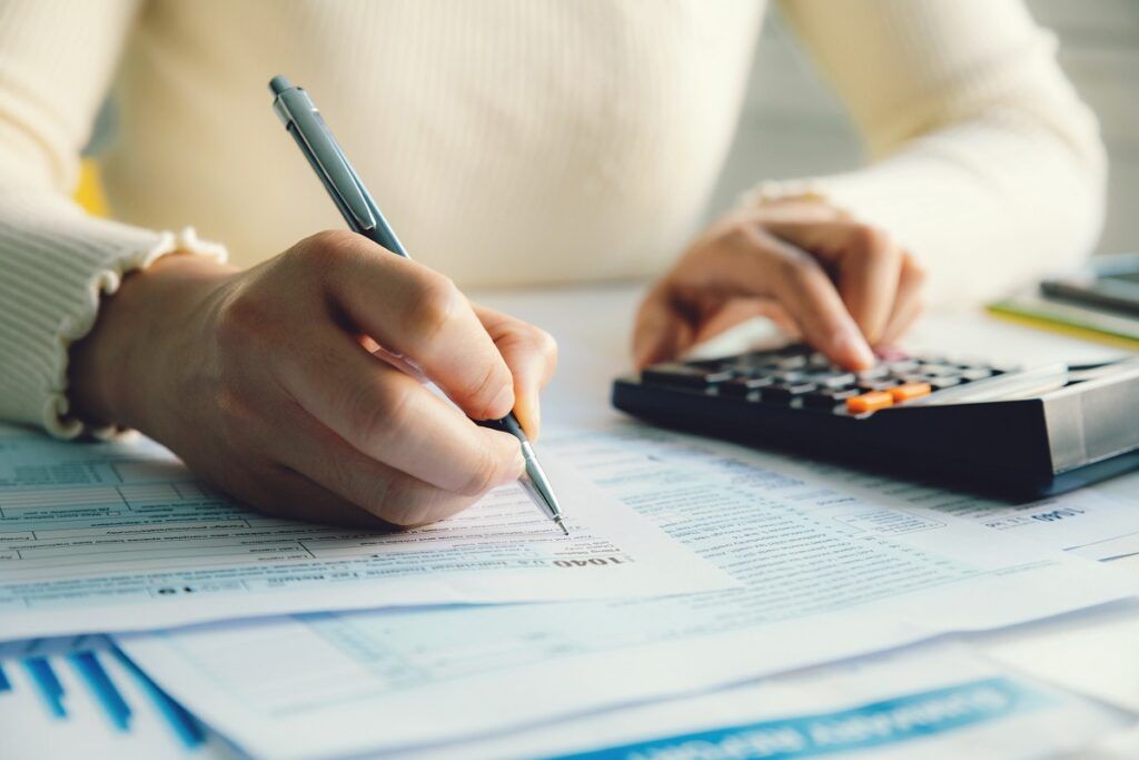 Uma pessoa segurando uma caneta e usando uma calculadora