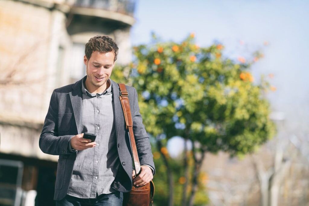 Homem usando o celular andando na rua