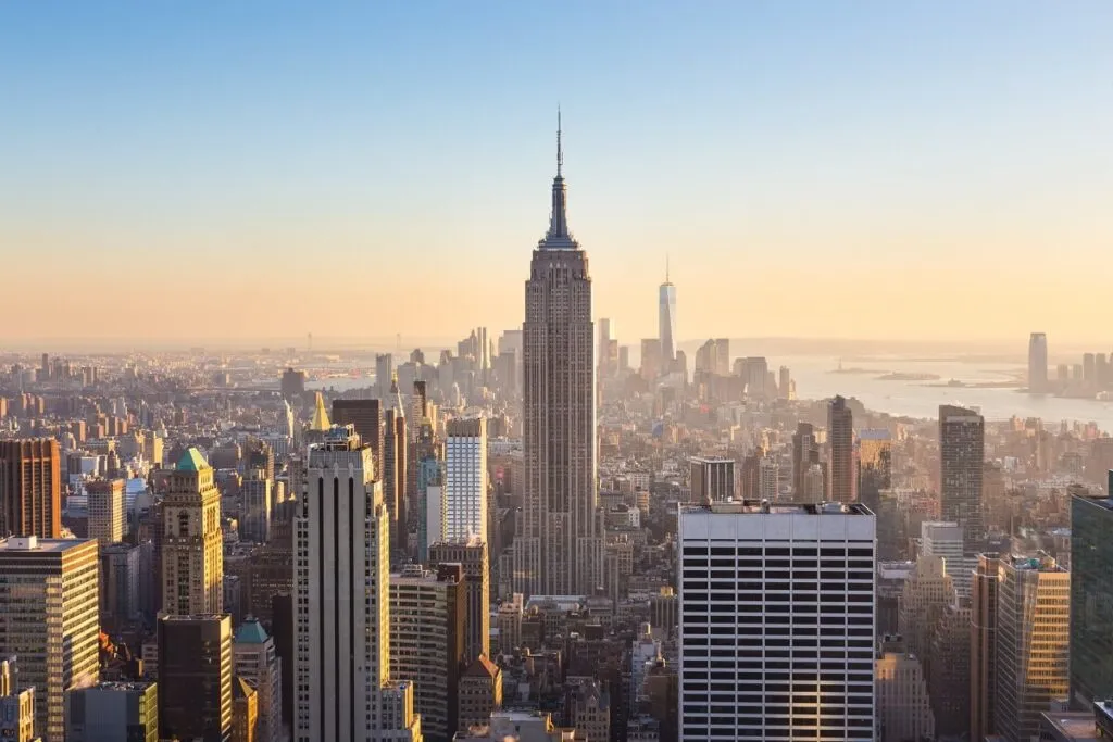 O horizonte do centro de Manhattan com iluminado Empire State Building e arranha-céus ao pôr do sol.