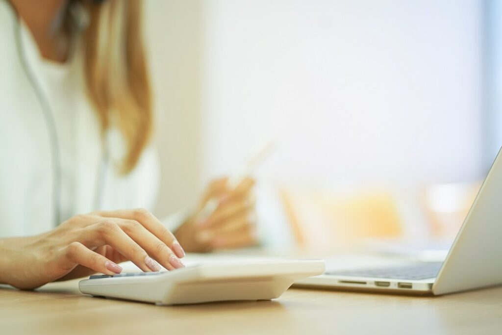 Mulher com notebook e com uma calculadora