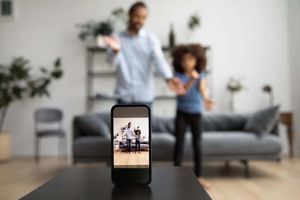 Pai e filha dançando e gravando para o TikTok em uma sala de estar