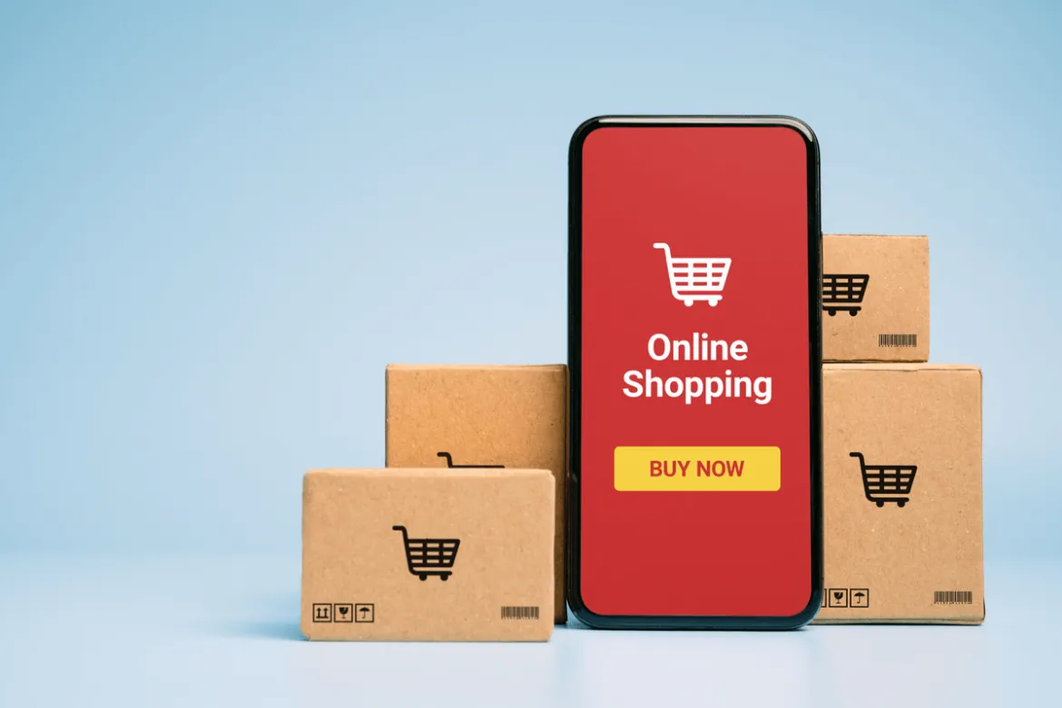 Imagem de um celular escrito "Online Shopping" apoiado em diversas caixas