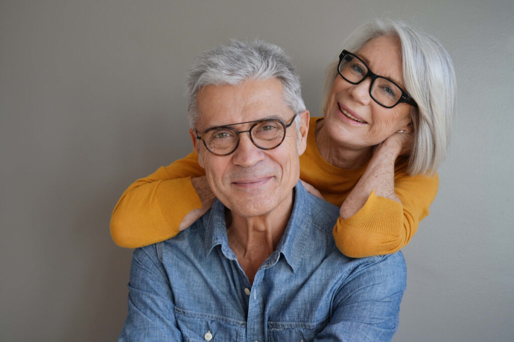 Um casal de idosos sorridentes olhando para a cãmera