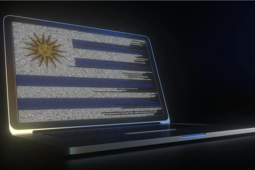 Imagem de um notebook aberto com códigos de programação na tela que formam o desenho da bandeira do uruguai