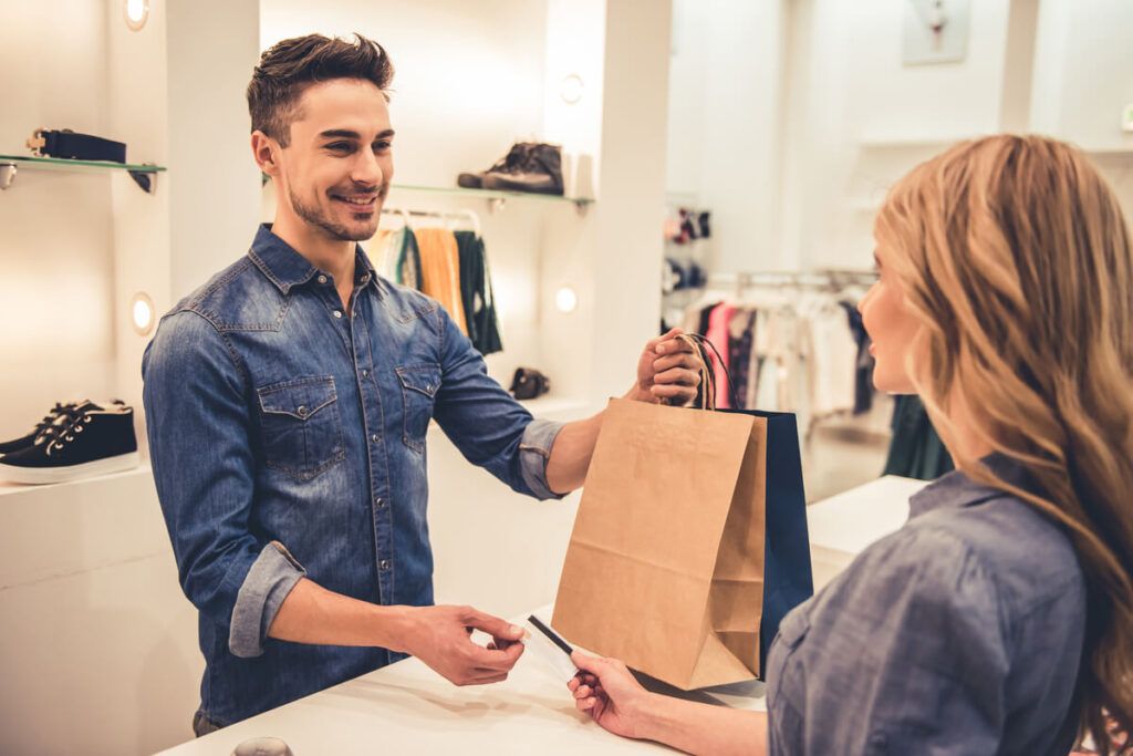 Vendedor entregando a sacola com as compras para a cliente, representando o brand awareness.