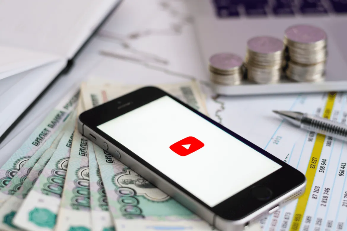 celular com o logotipo do YouTube na tela em cima de notas de dinheiro