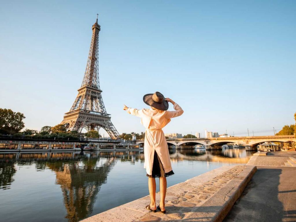 Mulher de costas apontando para a Torre Eiffel.