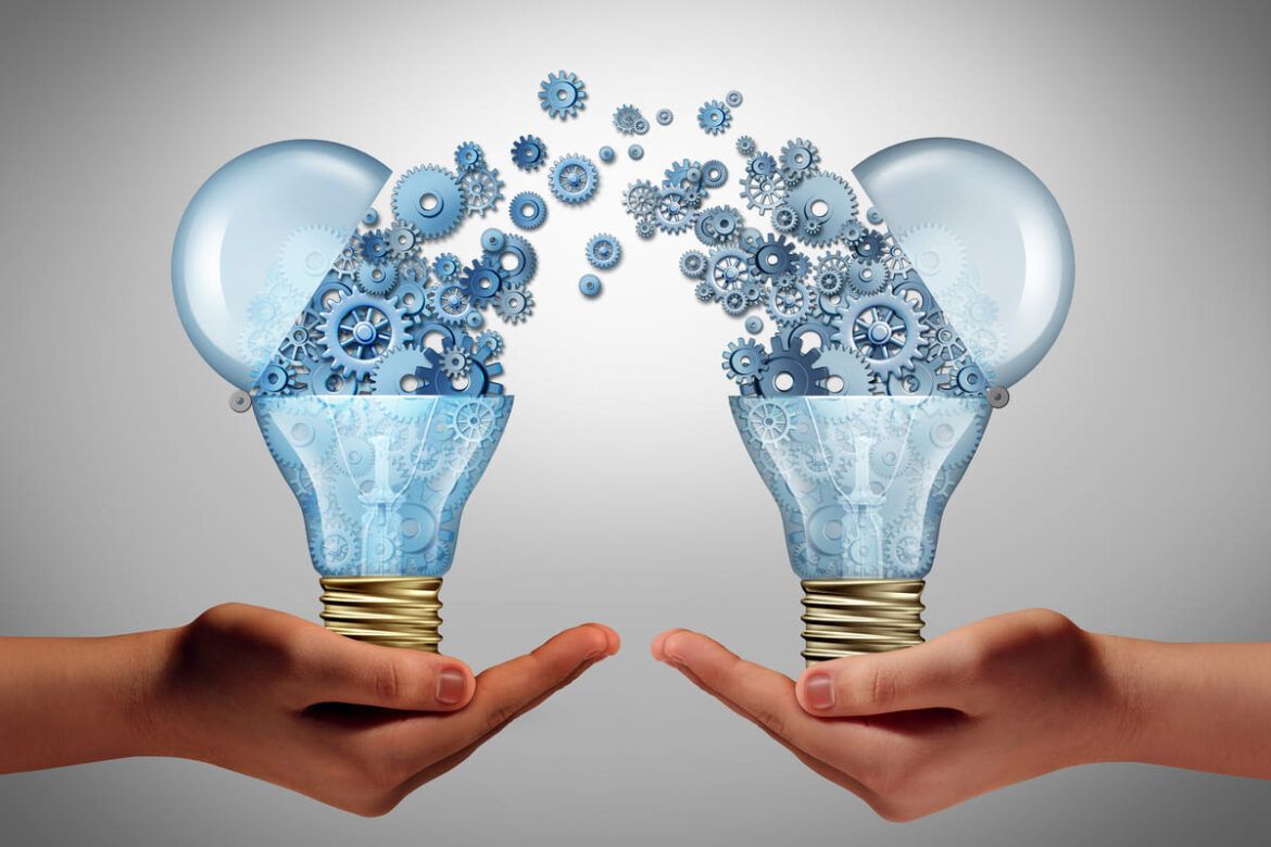 Mão segurando lâmpadas com ideias representando a Open Innovation.