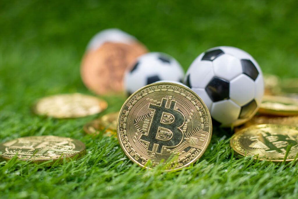 Imagem de várias moedas de Bitcoin e bolas de futebol em um gramado