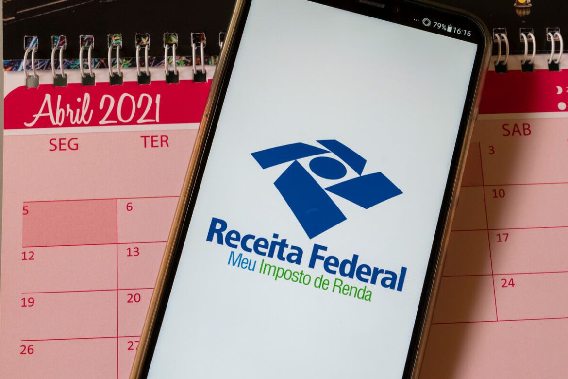 Foto de um celular com o aplicativo da Receita Federal aberto em cima de um calendário