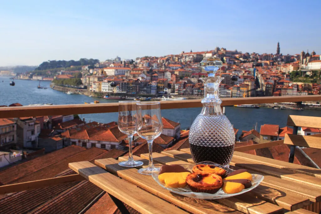 Culinária portuguesa: mesa com torta de ovo e vinho, com vista para o rio no Porto