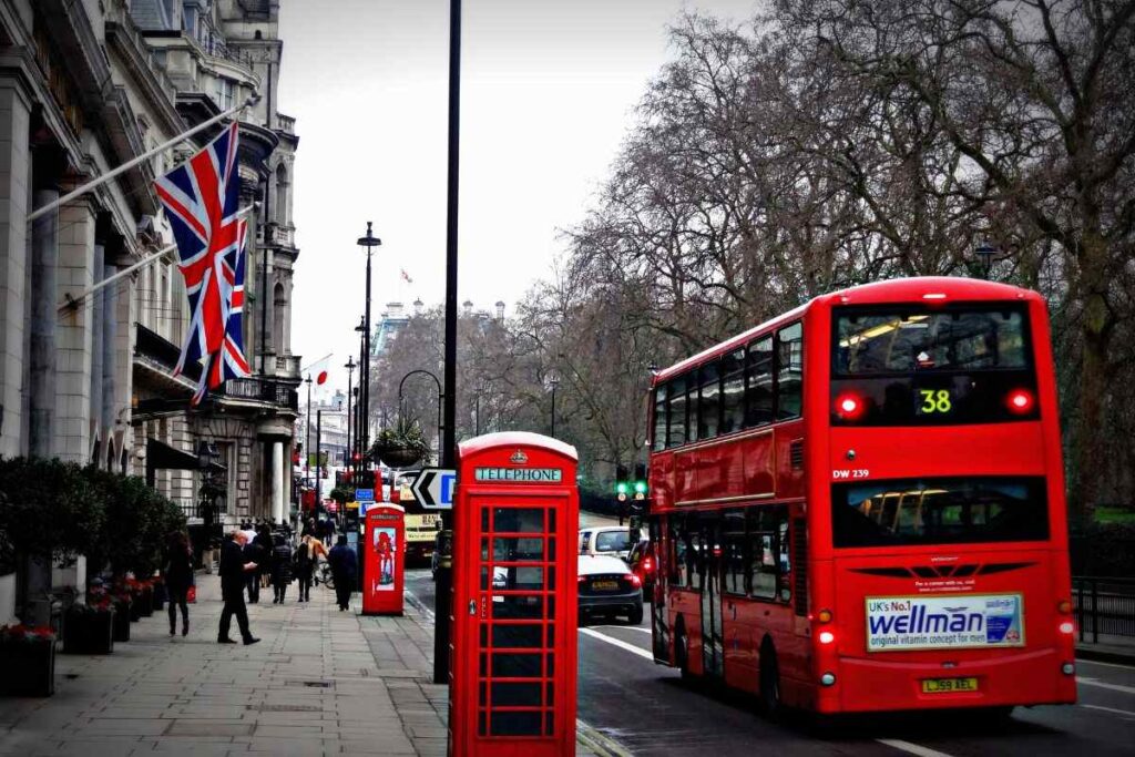 Rua em Londres com ônibus vermelho e pessoas caminhando.
