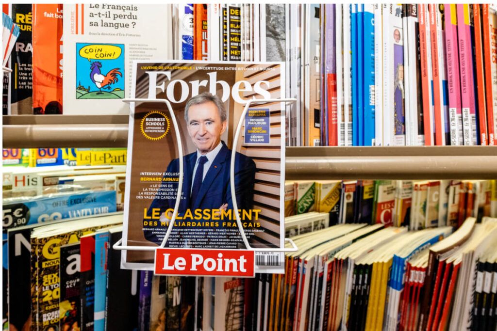 Foto de uma revista da Forbes com Bernard Arnault e, ao fundo, uma estante cheia de livros