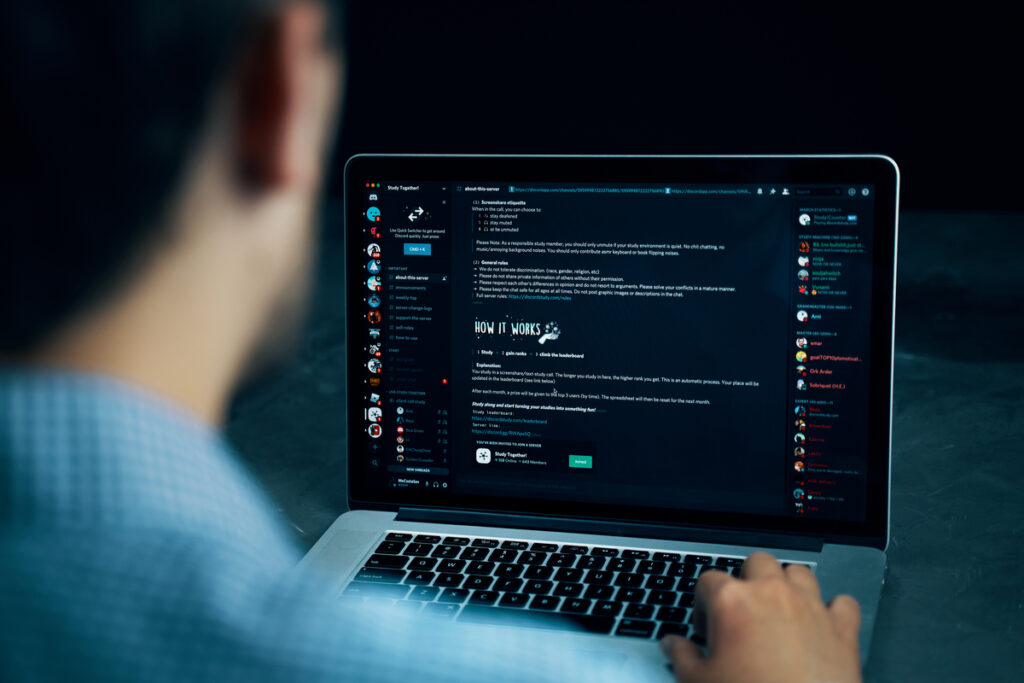 homem mostrando o funcionamento do discord no notebook