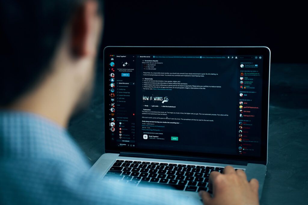 homem mostrando o funcionamento do discord no notebook 