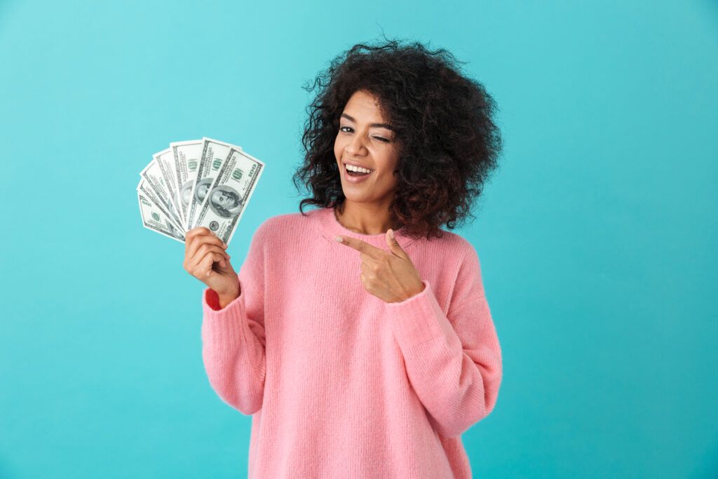 mulher feliz apontando para o dinheiro que ganhou usando o aplicativo sweatcoin