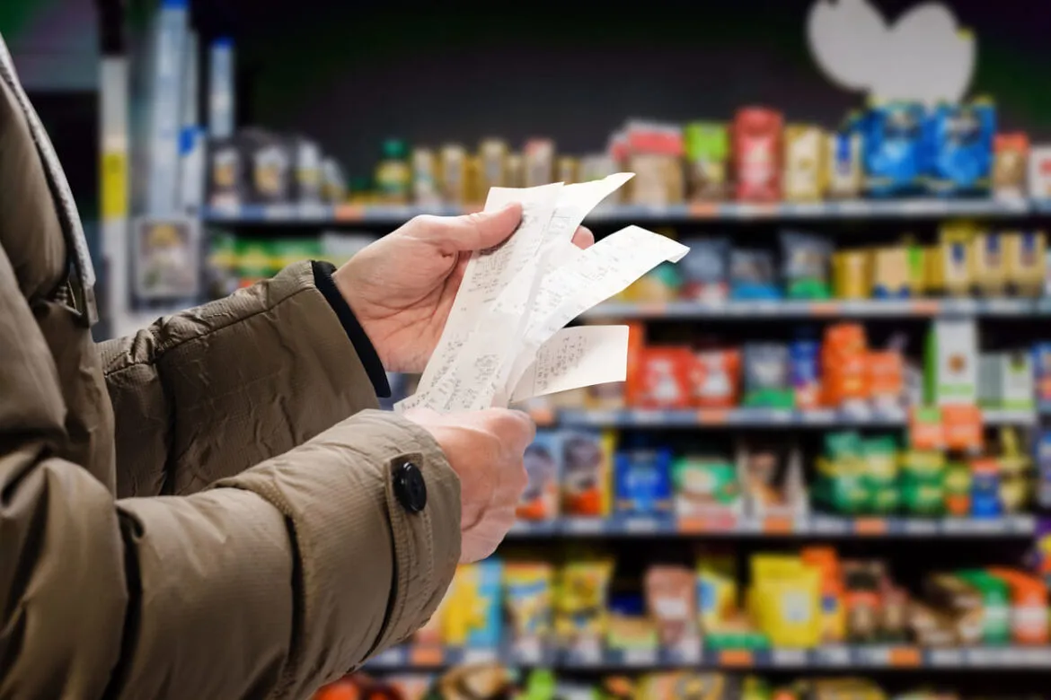 Homem confere extrato em supermercado que afeta o INPC acumulado 2022