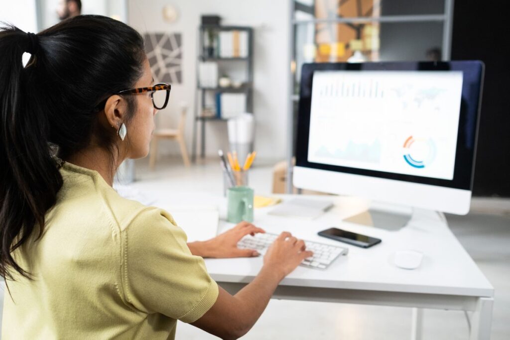 Mulher analisando dados do Adsense no computador.