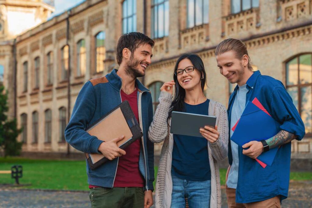 Universitários conversando em frente a Universidade de Cambridge.