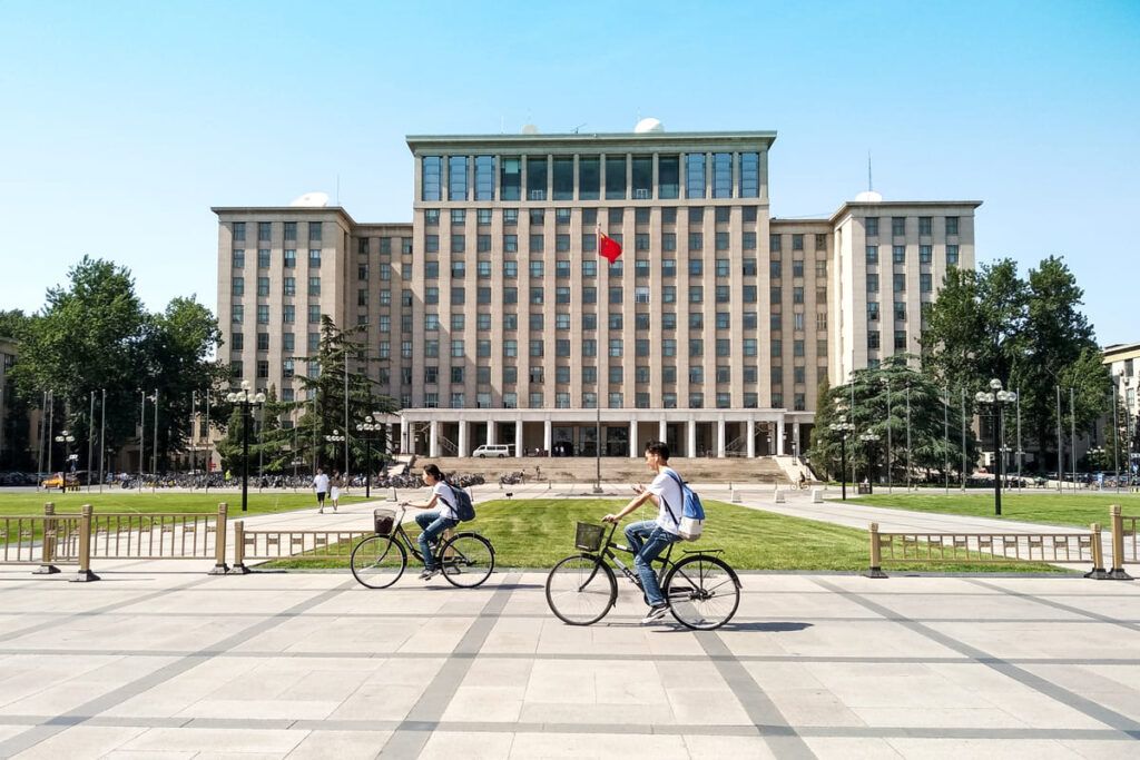 Imagem mostrando estudantes em bicicletas e ao fundo uma universidade chinesa