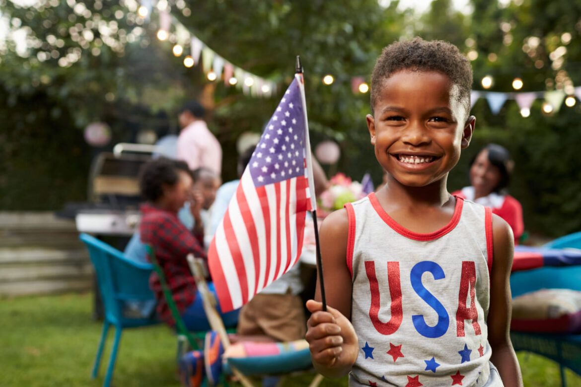Menino preto com a bandeira dos Estados Unidos em comemoração ao dia 4 de julho